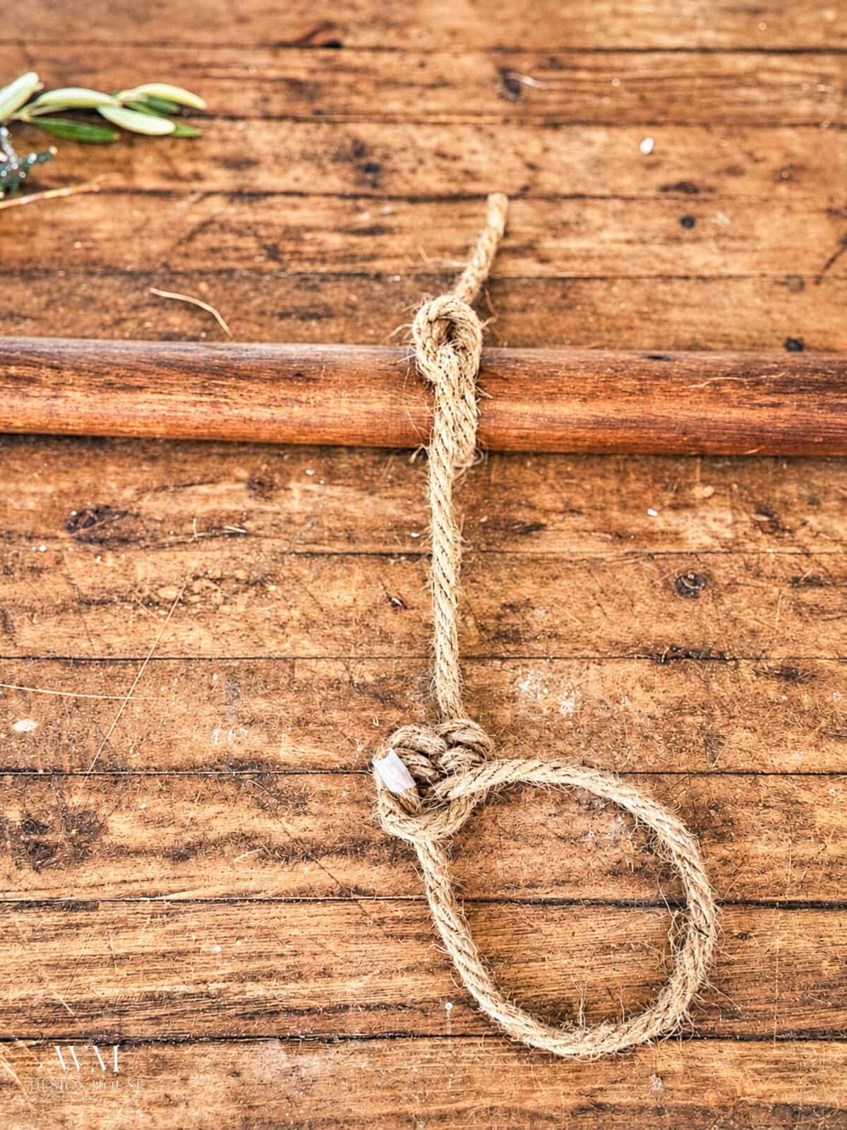 Jute rope tied in a loop around a wooden rod to create a leaf knot. 