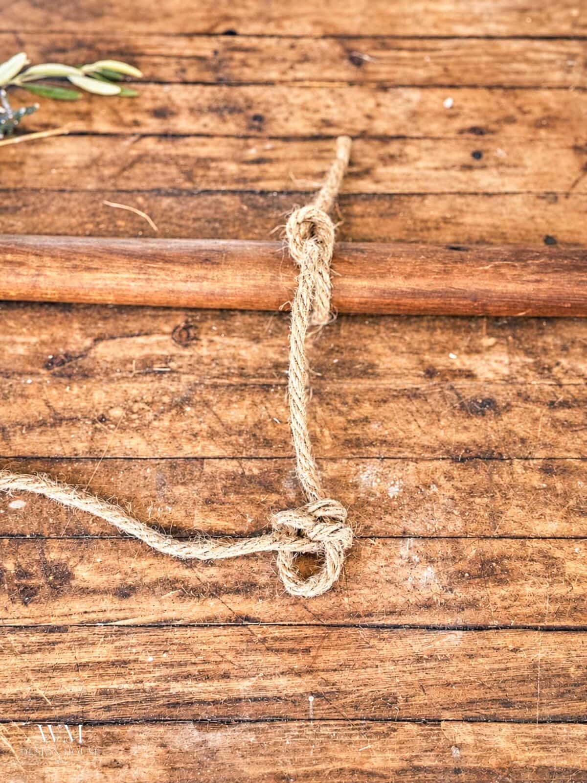 A length of jute rope tied around a wooden rod, featuring a loop at the bottom.