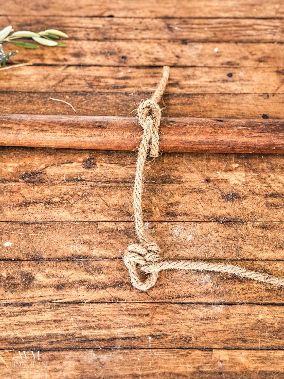 A length of twine tied to a wooden rod, featuring a leaf knot.