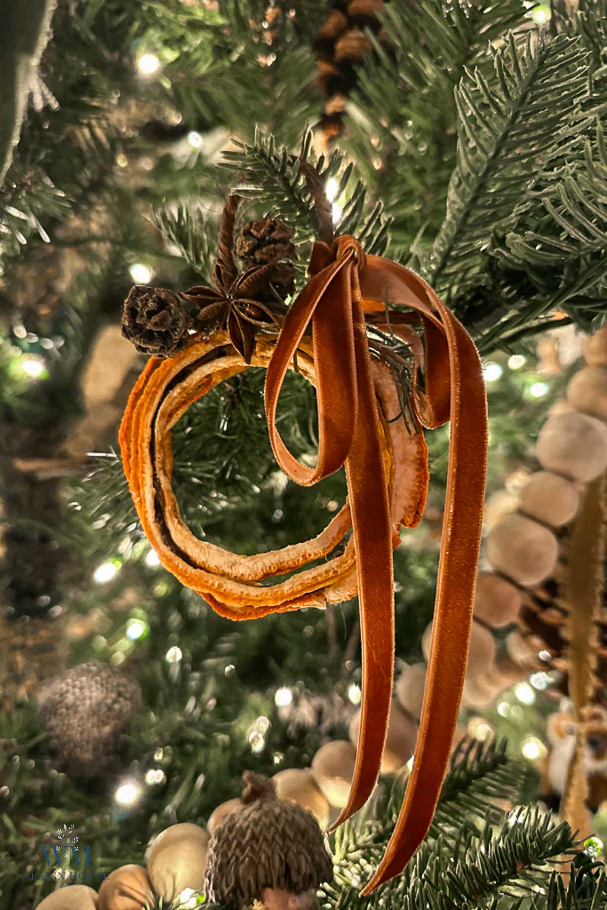 Christmas tree ornament made of dried orange slices, a star anise, and tiny pinecones, tied with a velvet ribbon.