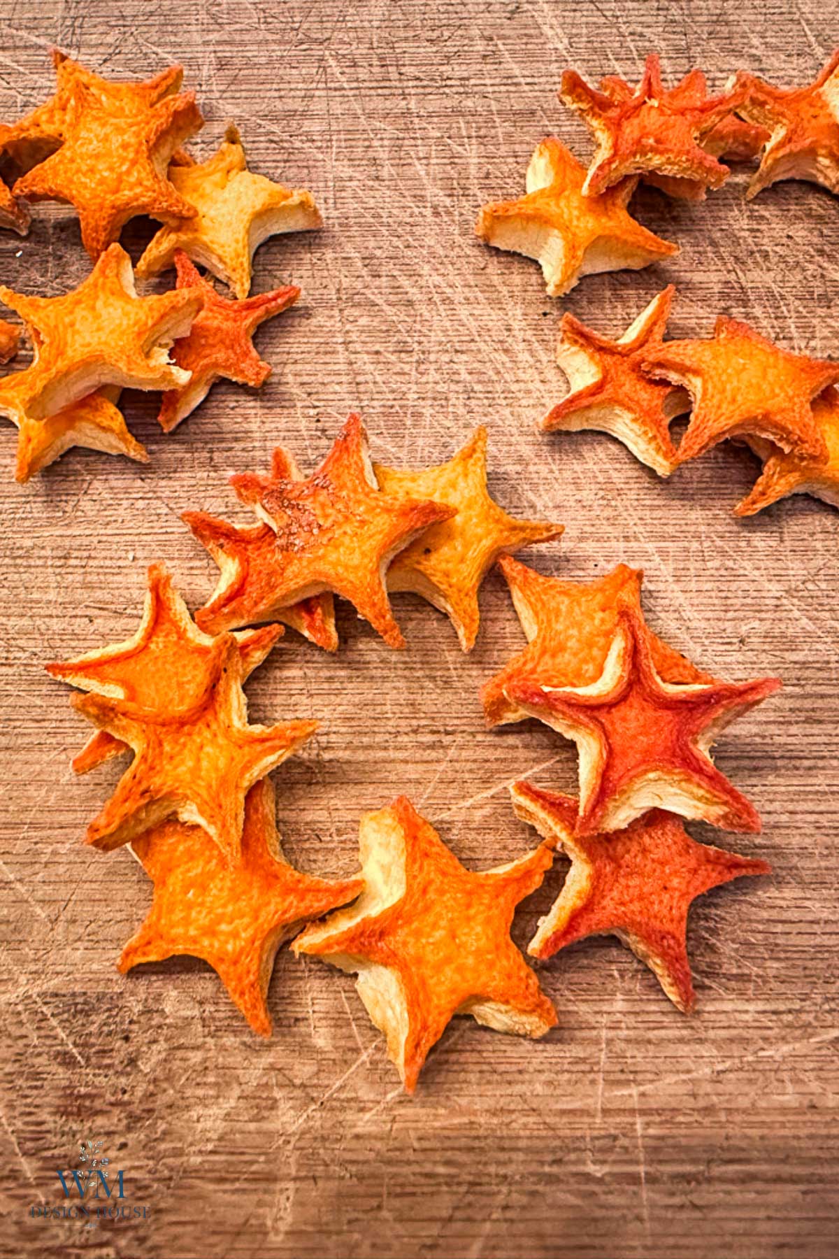 Dried orange slices cut into star shapes arranged on a wooden cutting board.