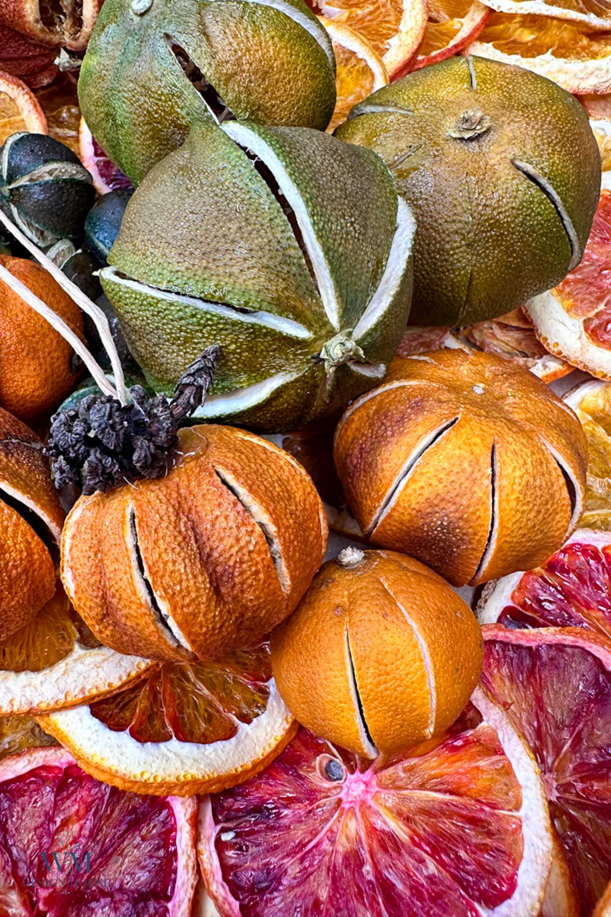 A collection of dried whole citrus fruits and sliced oranges and blood oranges.