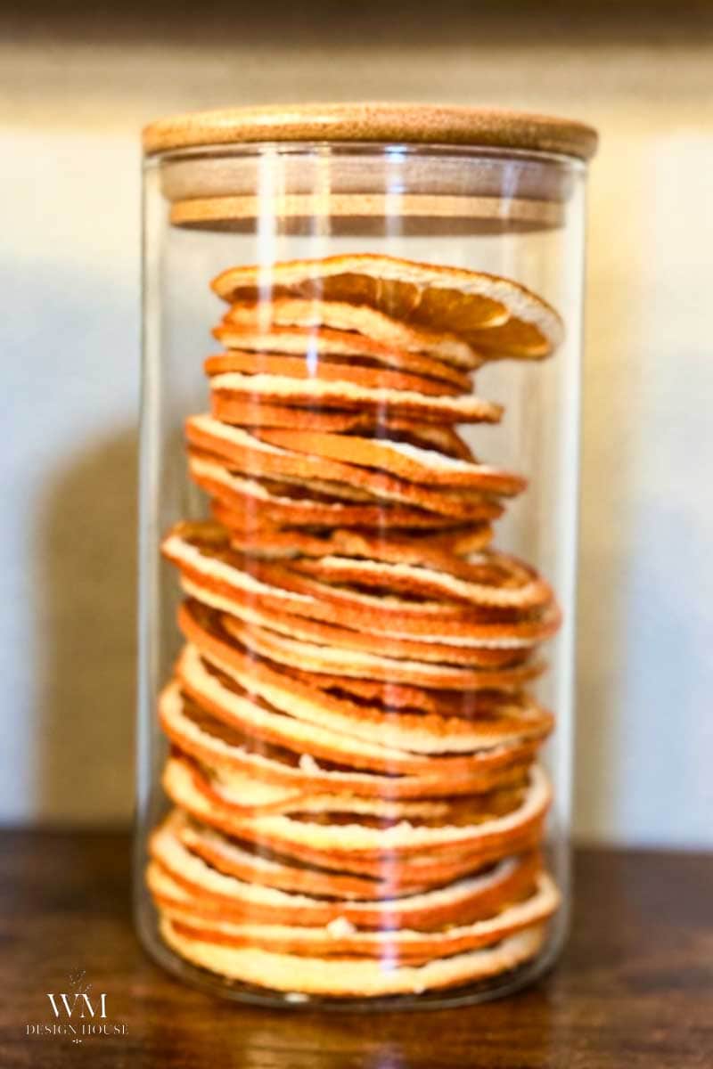 A tall glass jar filled with a stack of dried orange slices.