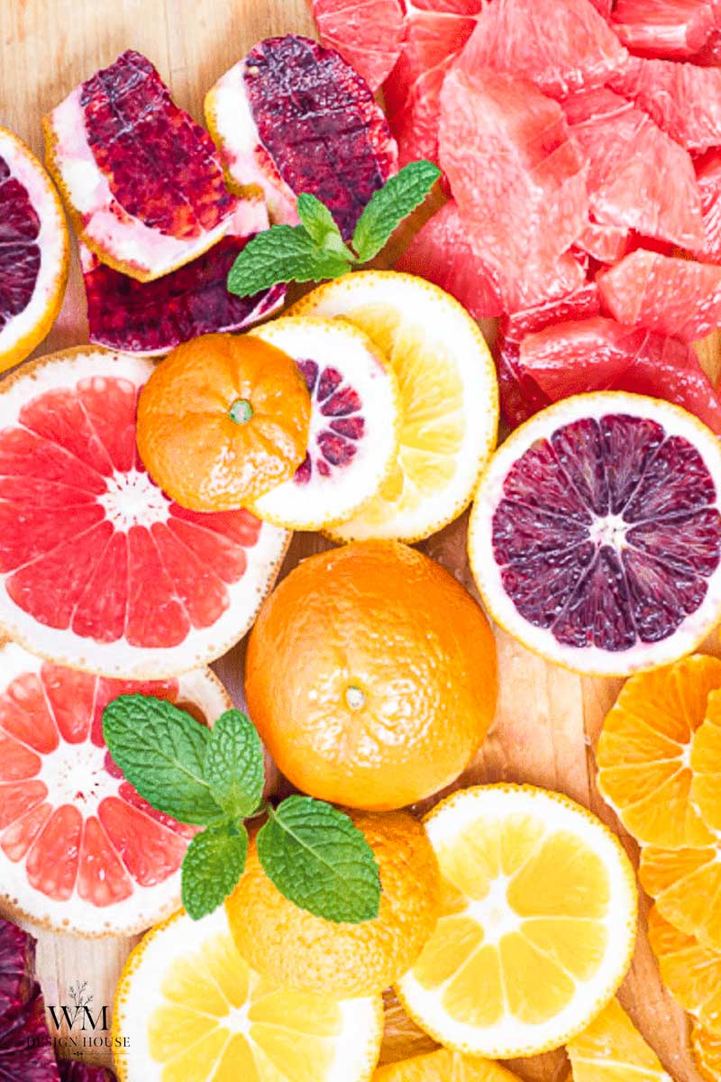 A collection of fresh and dehydrated orange slices, blood oranges, and grapefruit, garnished with fresh mint leaves.
