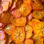 A pile of thinly sliced, dried persimmons showing their circular, star-shaped centers.