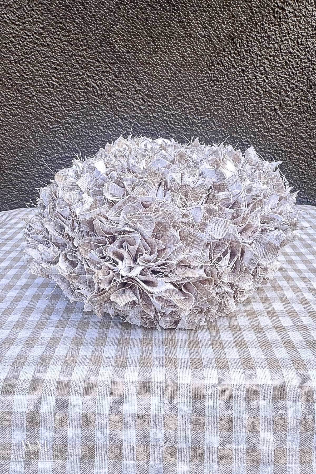 Decorative no sew fabric pumpkin topped with ruffled tan and white checkered scraps.