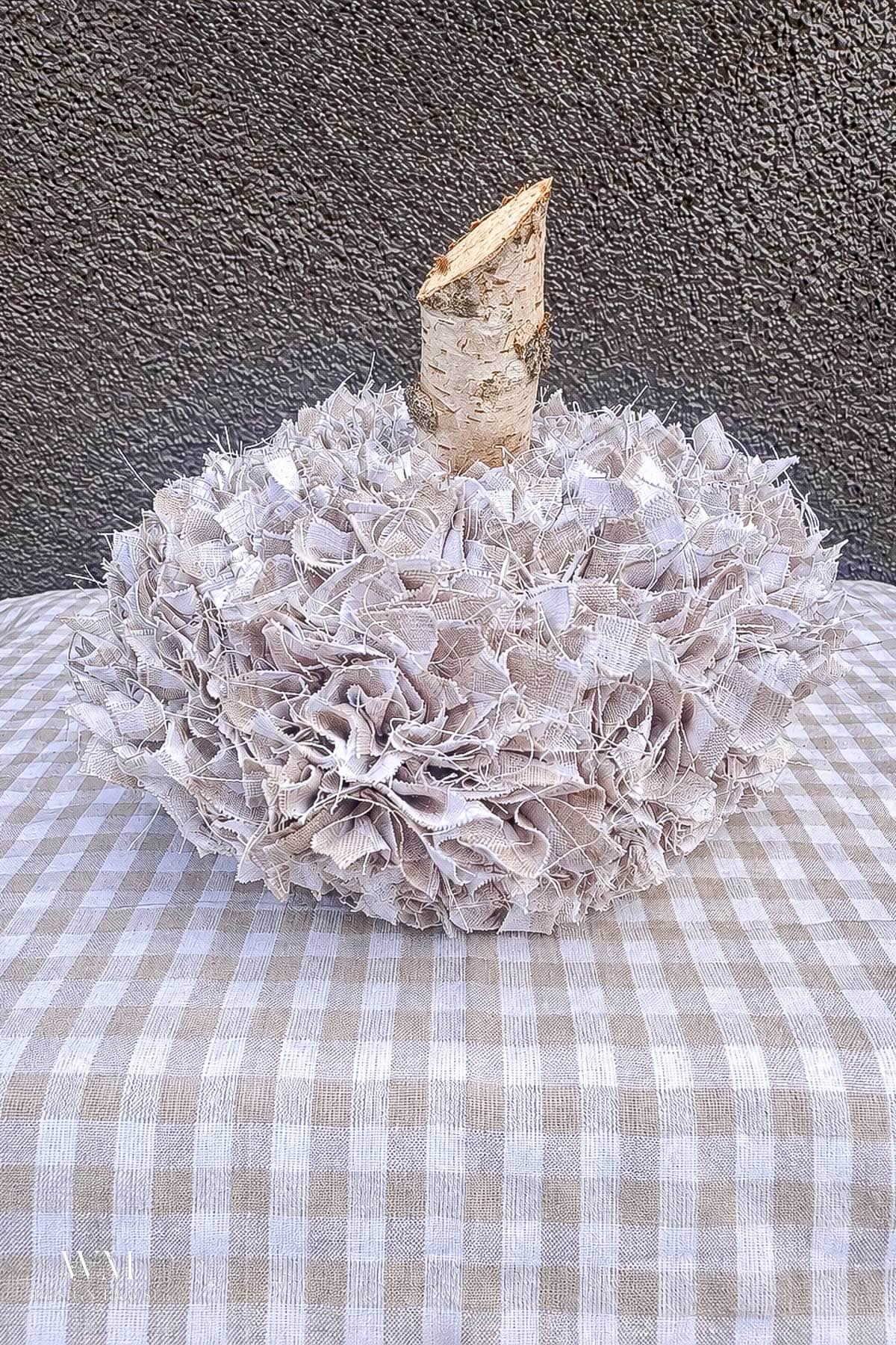 No sew fabric pumpkin made of 2" fabric squares poked into a foam pumpkin with a natural birch wood stem.