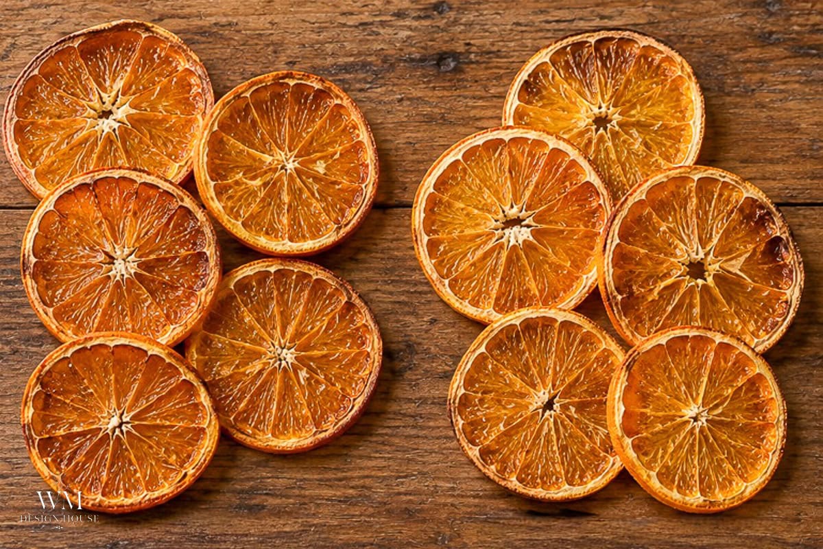 Eight dehydrated orange slices arranged on a dark wooden surface.
