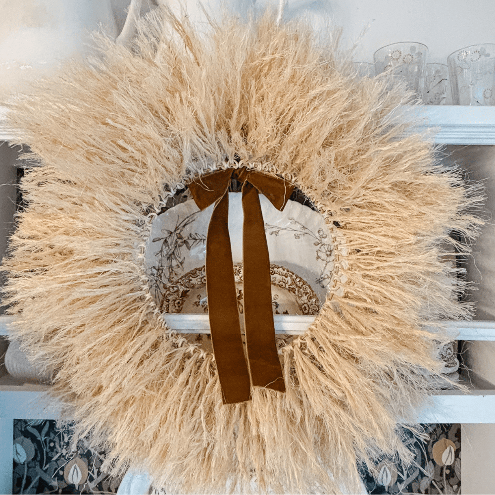 A round wreath made of light-colored sisal rope, accented with a brown velvet ribbon.