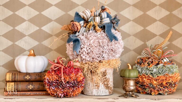 Autumnal decor featuring no sew fabric pumpkins, a birch log base, and a small stack of books.