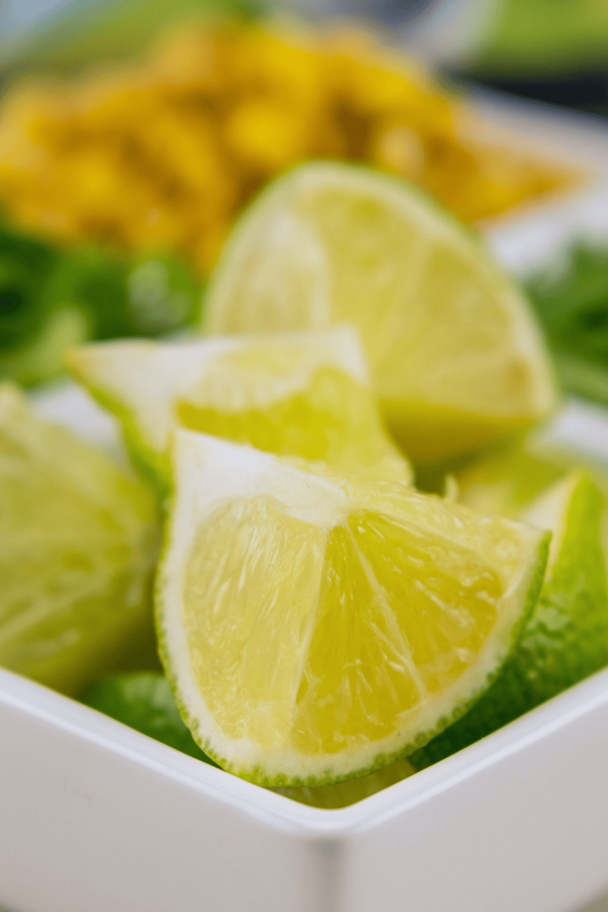 A close-up of lime wedges in a small white bowl served with homemade nachos.